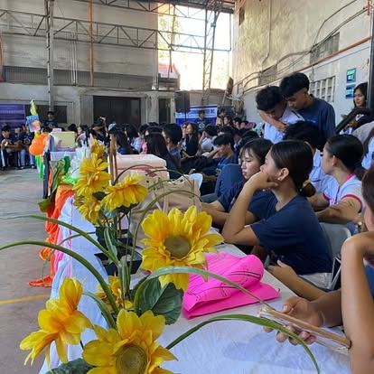 Students watching a campus program beside sunflower arrangements